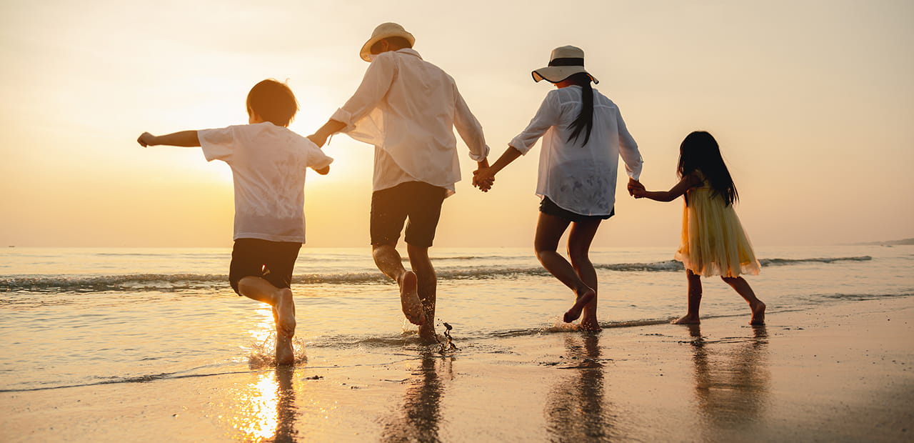 Happy Asian family at the beach during sunset.