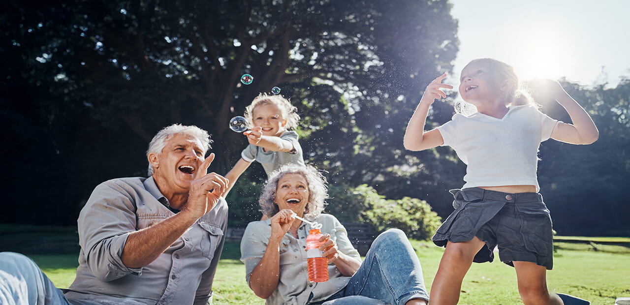 Grandparents, bubbles and children play in park happy together for fun, joy and outdoor happiness. 
