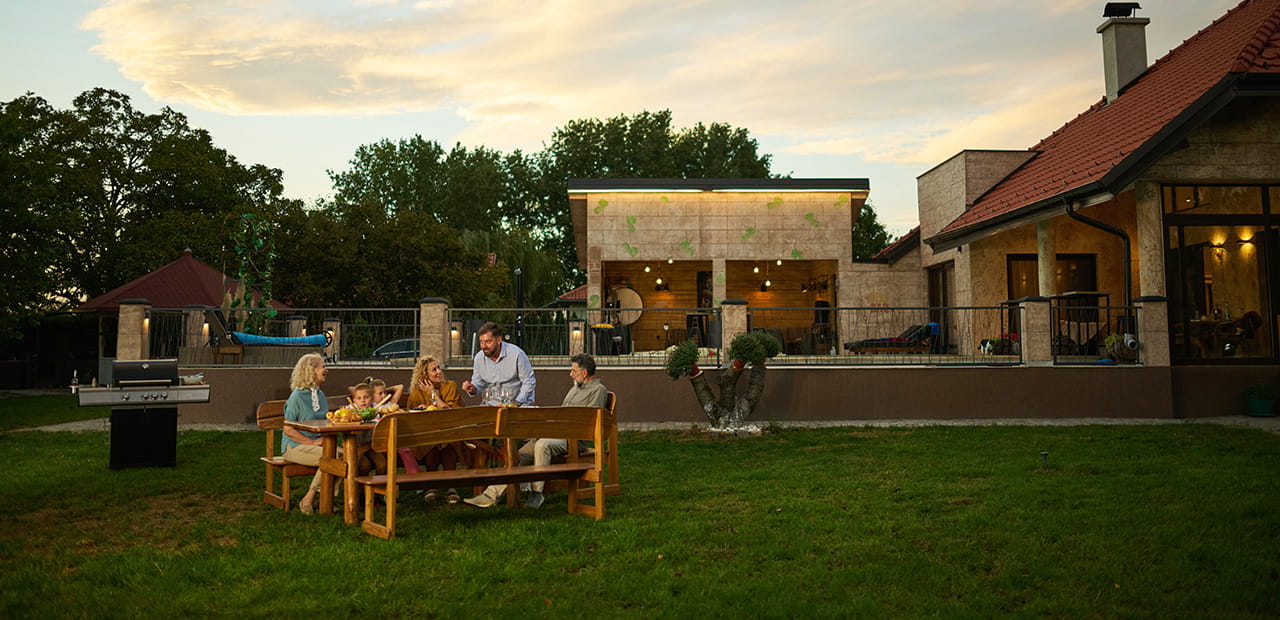Family enjoying backyard barbecue dinner party at sunset