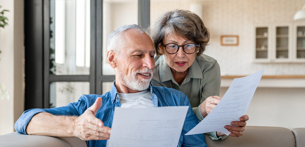 Caucasian senior spouses reading paperwork.