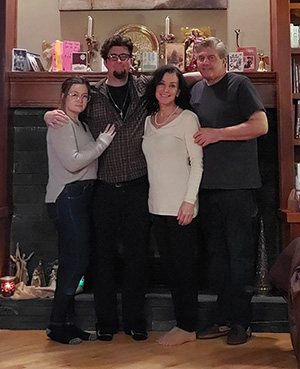 Two men and two women posing in front of a fire place.