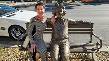 Woman sitting on a bench next to a statue.