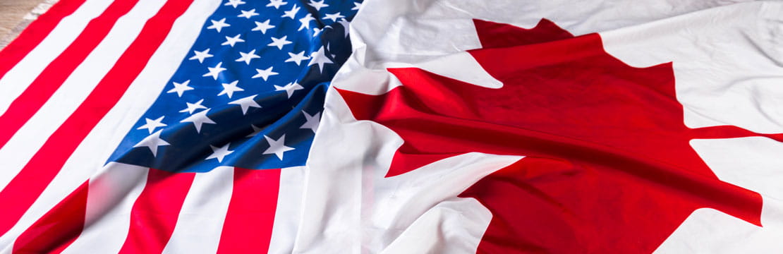 US and Canadian flags laying side by side.