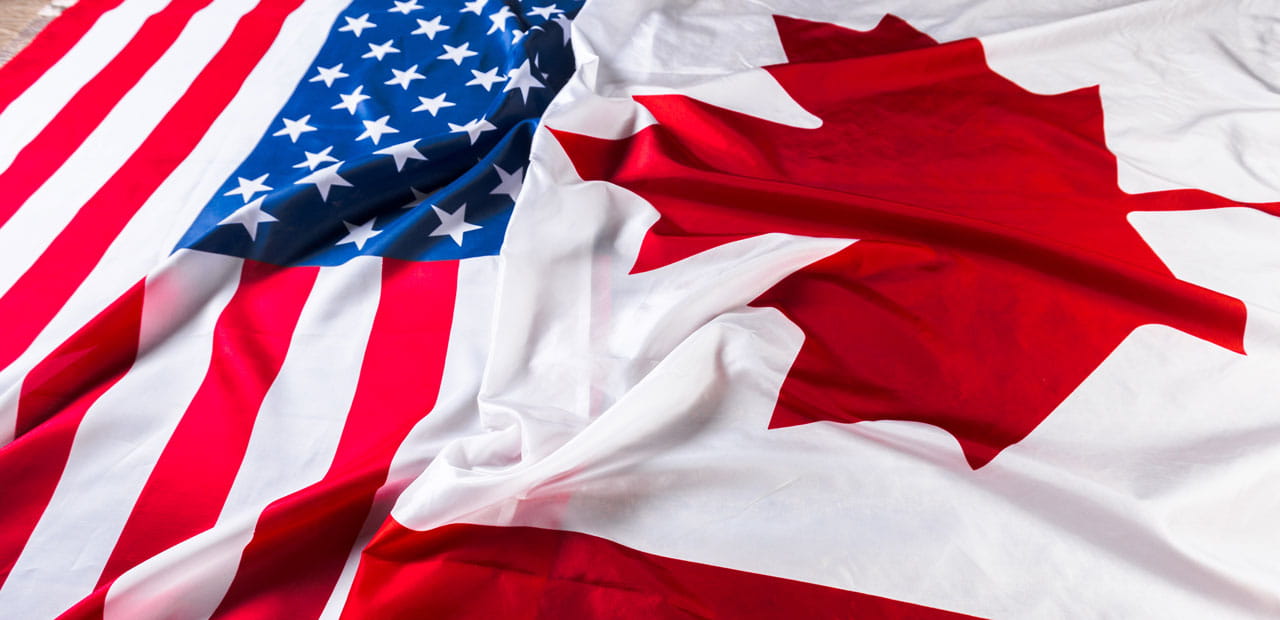 US and Canadian flags laying side by side.