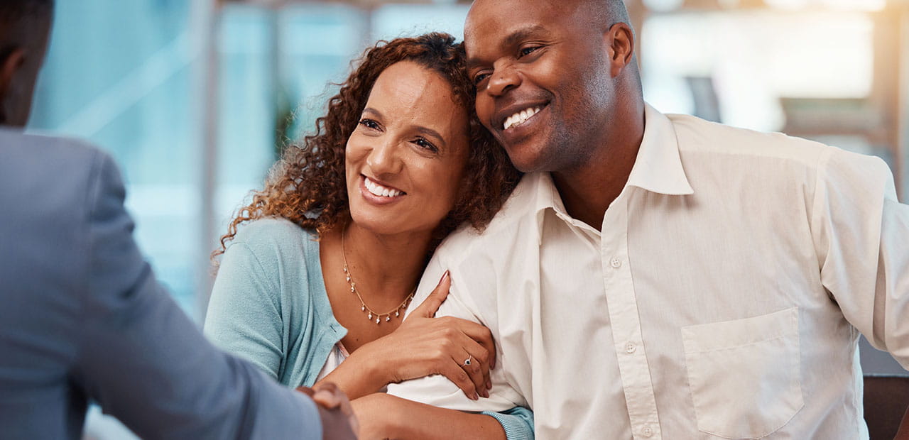 Happy couple came to a successful agreement with their insurance agent on a meeting in the office.