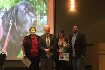 Group of people in front of image of dog